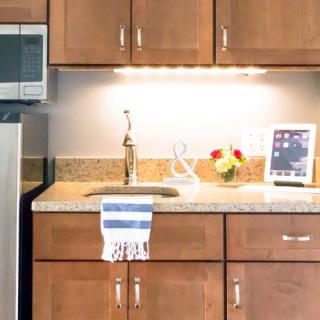 A modern kitchen with wooden cabinets, featuring a countertop sink and a decorative towel.