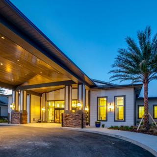 A modern building entrance illuminated at night with a palm tree nearby.