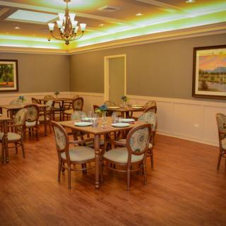 A cozy dining room setting with tables and chairs, elegant decor, and warm lighting.