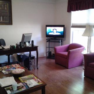 A cozy waiting room with a television, armchairs, and a desk.