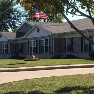 A well-maintained building with an American flag flying above, surrounded by manicured lawns.