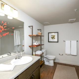 A modern bathroom with a sink, toilet, and decorative shelving.