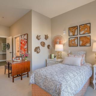 A cozy bedroom with a single bed, decorated with wall art and warm lighting.