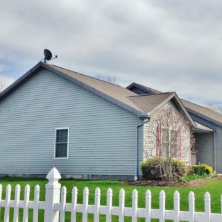 A suburban house with a white picket fence and a well-maintained lawn on a cloudy day.