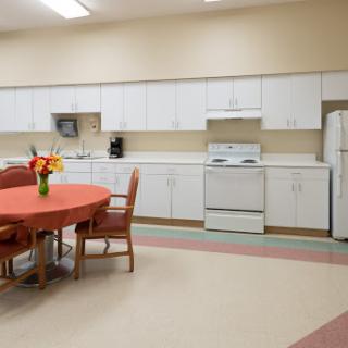 A spacious and bright kitchen with a dining area featuring a round table, chairs, and modern appliances.