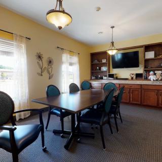 A well-lit conference room with a meeting table, chairs, and a TV on the wall.