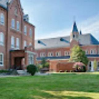 A picturesque brick building on a college campus with a well-maintained lawn.