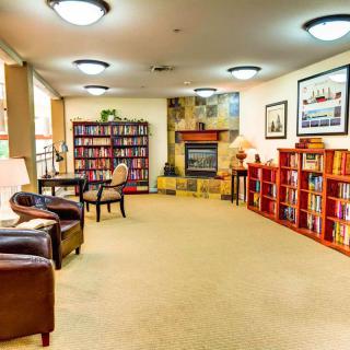 A cozy library with bookshelves, comfortable seating, and a fireplace.