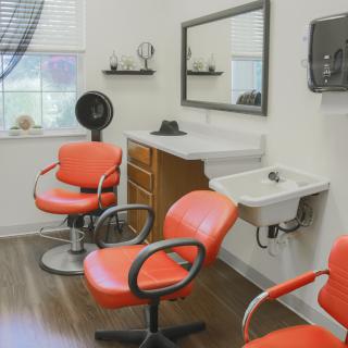 A modern hair salon with orange chairs and a large mirror.