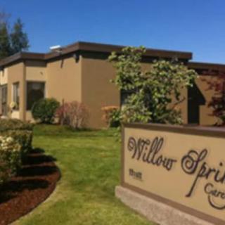 A brown building with a sign reading 'Willow Springs' surrounded by well-maintained landscaping.