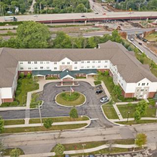 Aerial view of a large residential building with surrounding landscape and roads.