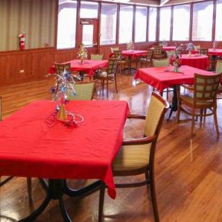 A cozy restaurant dining area with red tablecloths and wooden flooring.