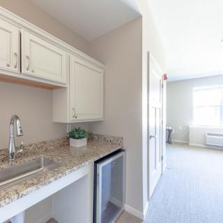 A small kitchenette with white cabinets, a granite countertop, and a sink.