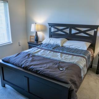 A neatly made bed in a cozy bedroom with a lamp and nightstand.