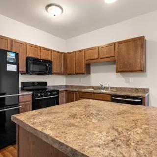 A modern kitchen featuring wooden cabinets, stainless steel appliances, and a spacious countertop.