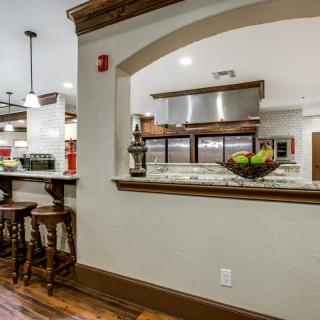 A modern kitchen with an open archway, featuring bar stools and wooden flooring.