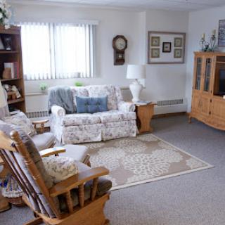 A cozy living room featuring comfortable seating, a bookshelf filled with books, and soft lighting.