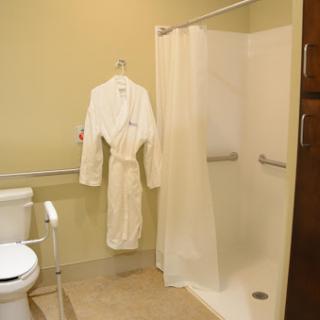 A cozy bathroom featuring a white robe hanging, a shower enclosure, and a toilet.