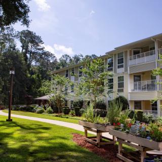 A scenic view of an apartment complex surrounded by lush greenery and a well-maintained lawn.