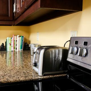 A cozy kitchen corner featuring a toaster, stove, and a stack of cookbooks on the granite countertop.