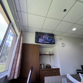 A hospital room featuring a television mounted on the wall and a view through the window.