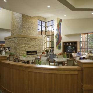 A modern lobby interior featuring a stone fireplace, seating area, and large windows.