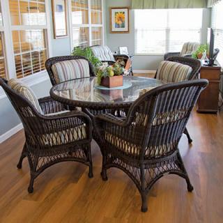 A cozy dining area featuring a round table with rattan chairs in a sunlit room.