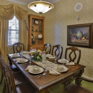 A traditional dining room setup with an elegant table and chairs, complete with place settings and decorative elements.