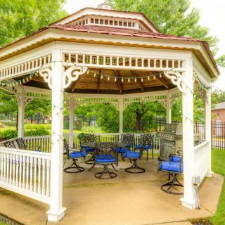 A charming gazebo with blue-cushioned chairs set in a lush garden.