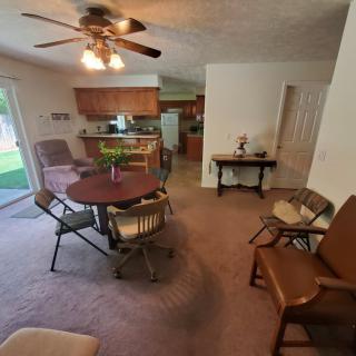 A cozy living room with a dining area and view into the kitchen, featuring comfortable seating and a ceiling fan.
