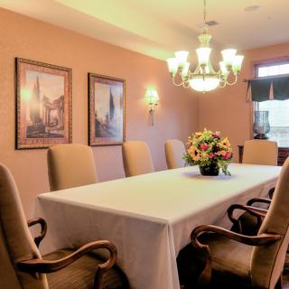 A traditional dining room with a large table, upholstered chairs, and a chandelier.