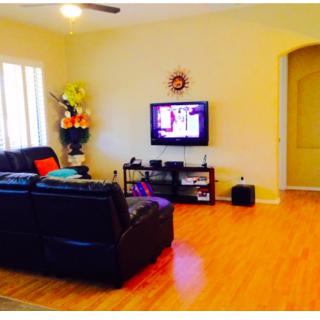 A cozy living room featuring a leather sofa and a wall-mounted television.