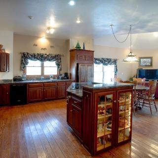 Spacious kitchen with a central island, wooden cabinets, and a dining area with hardwood flooring.
