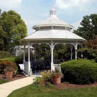 A white gazebo surrounded by lush greenery and a well-maintained garden path.