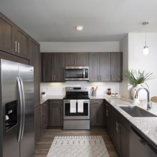 A modern kitchen with stainless steel appliances and dark cabinetry.