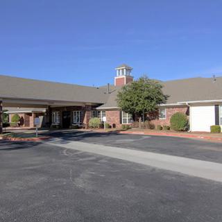 A modern brick building with a large parking lot under a clear blue sky.
