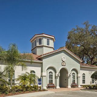 A residential building with a prominent entrance and well-maintained landscaping under a clear blue sky.