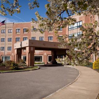 A brick building with a covered entrance and surrounding trees in bloom.