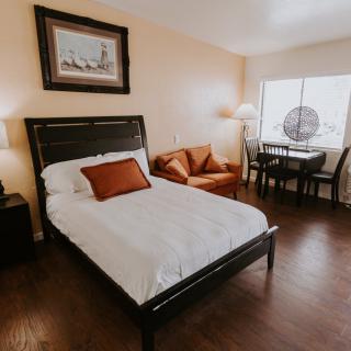 A cozy bedroom with a bed, sofa, and dining area.