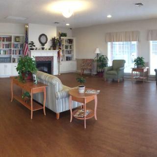A cozy living room with a sofa, bookshelf, fireplace, and hardwood floor.