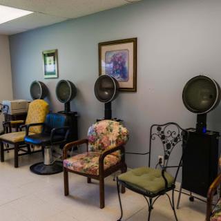 A cozy waiting area in a salon featuring various chairs and hairdryers.