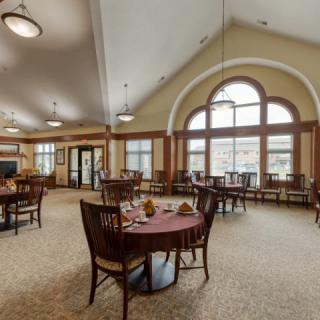 A spacious and elegantly furnished dining room with large arched windows.