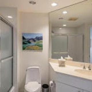 A modern bathroom featuring a toilet, sink, and shower with a large mirror.