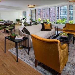A modern living room with stylish furniture and large windows offering a city view.