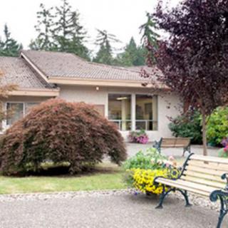 A cozy house with a landscaped garden and a bench in the foreground.