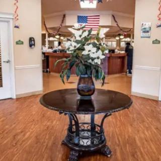 A decorated lobby area featuring a central table with flowers and an American flag in the background.