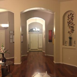 A warmly lit hallway with wooden floors and decorative arches.