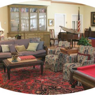 A cozy living room featuring a mix of seating, a piano, and a pool table.