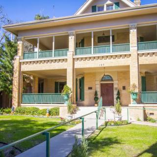 A two-story house with a large porch and well-maintained lawn.