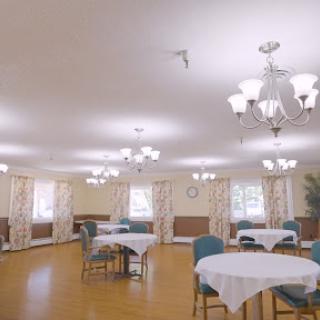 A bright and spacious dining area with tables and chairs, elegantly decorated with floral curtains and warm lighting.